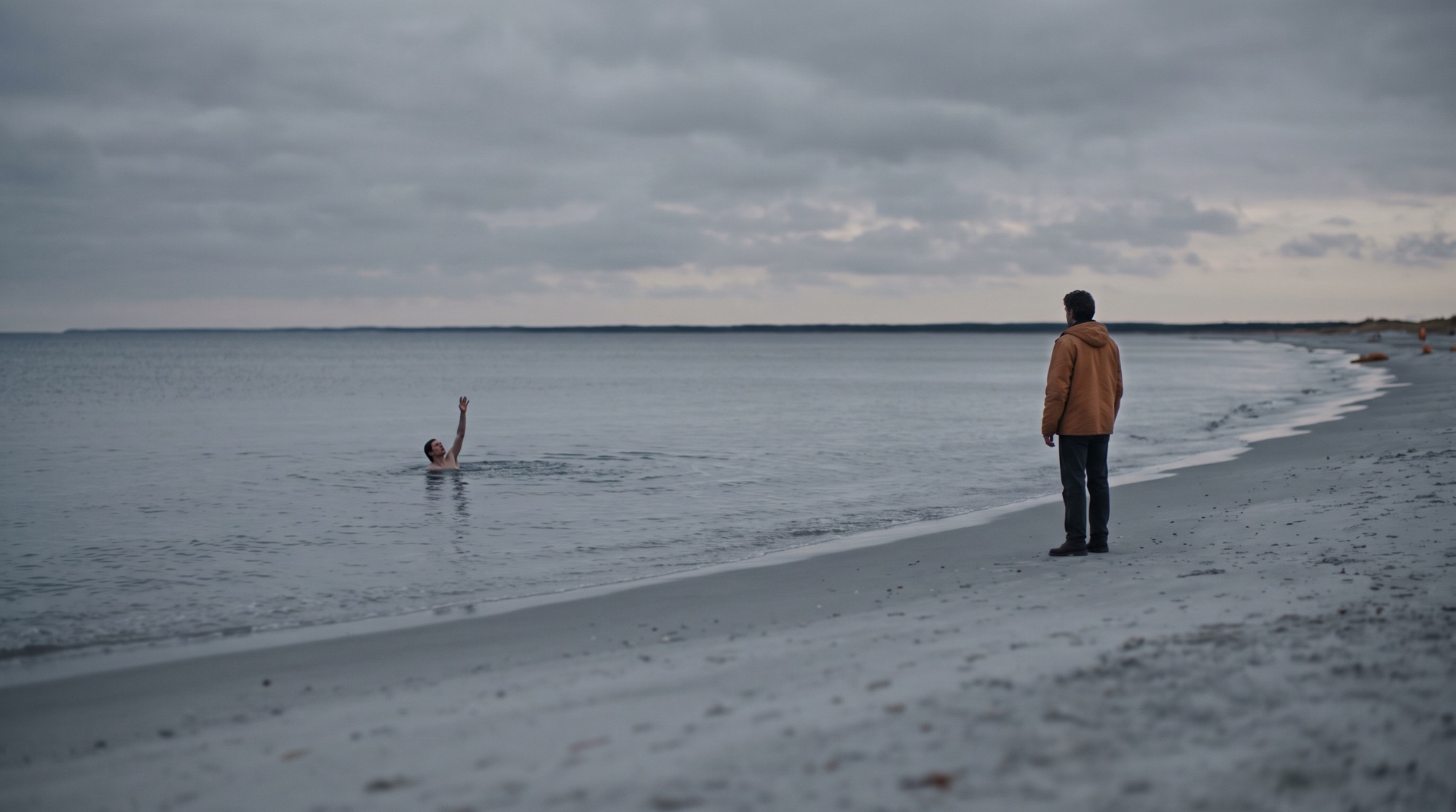 Fotorealistisches Kino-Still bei bewölkter Dämmerung. In der ruhigen grauen See reicht ein Mensch, bis zur Brust im Wasser, eine Hand zum Ufer hin nach oben. In einigem Abstand am Sandstrand steht ein zweiter Mensch still da, die Hände unten, und sieht nur zu. Gedämpfte Farben, ein warmer Lichtakzent.